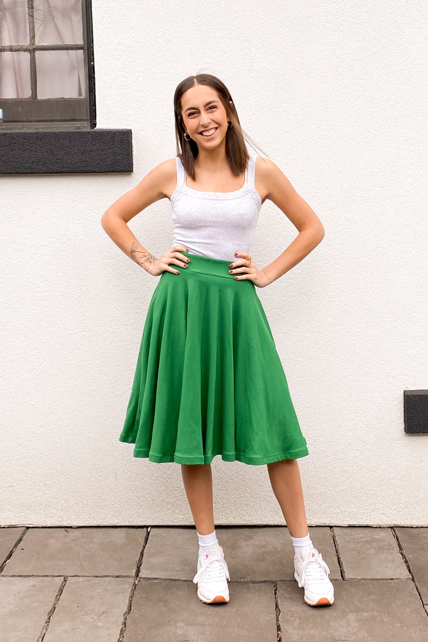 Front view of the model with hands on hips wearing a green knee length circle skirt