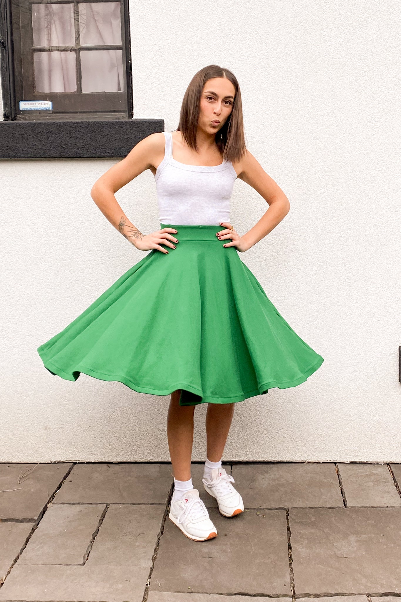 Front view of the model twirling in a green knee length circle skirt