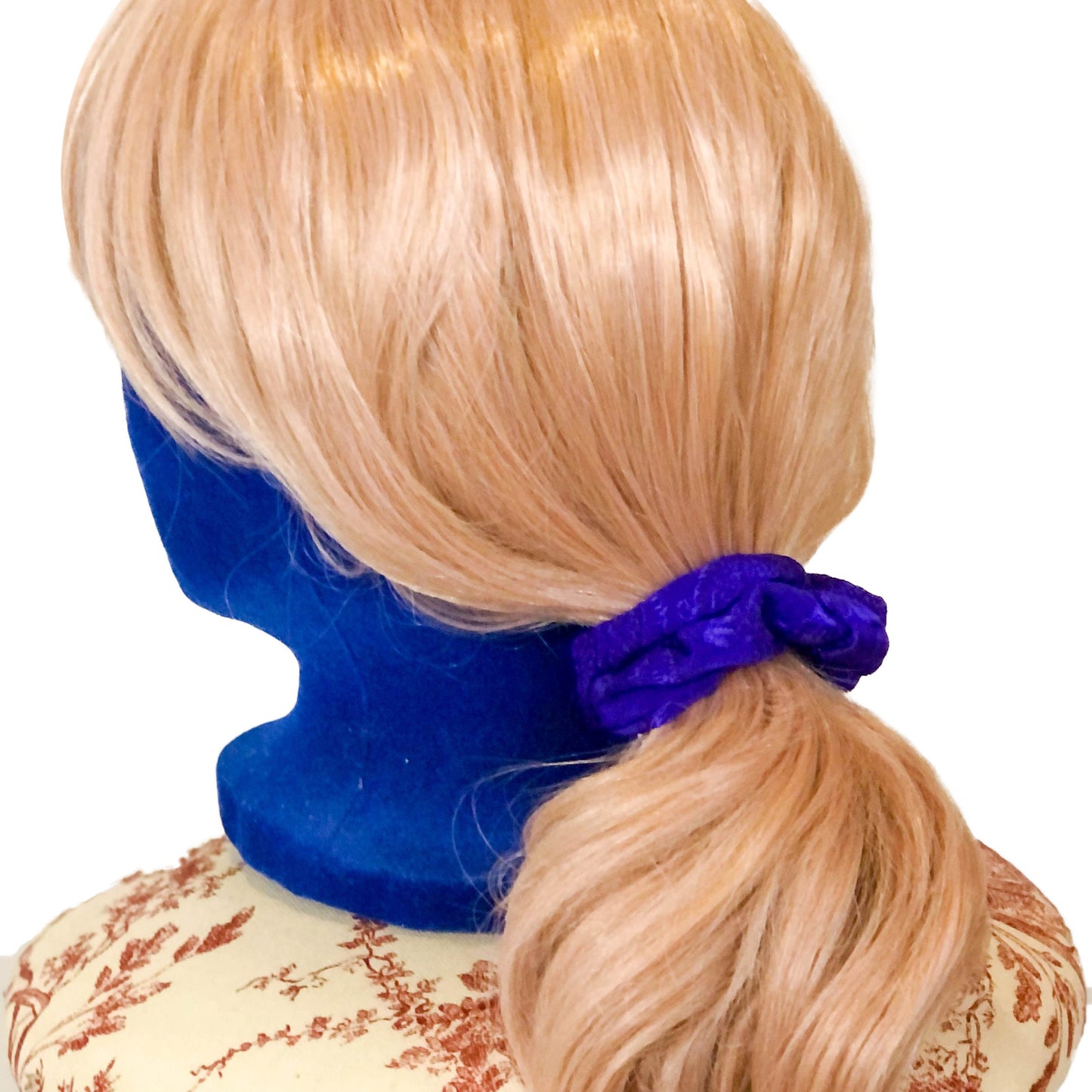 Photo of a scrunchie made of woven purple material on a wig