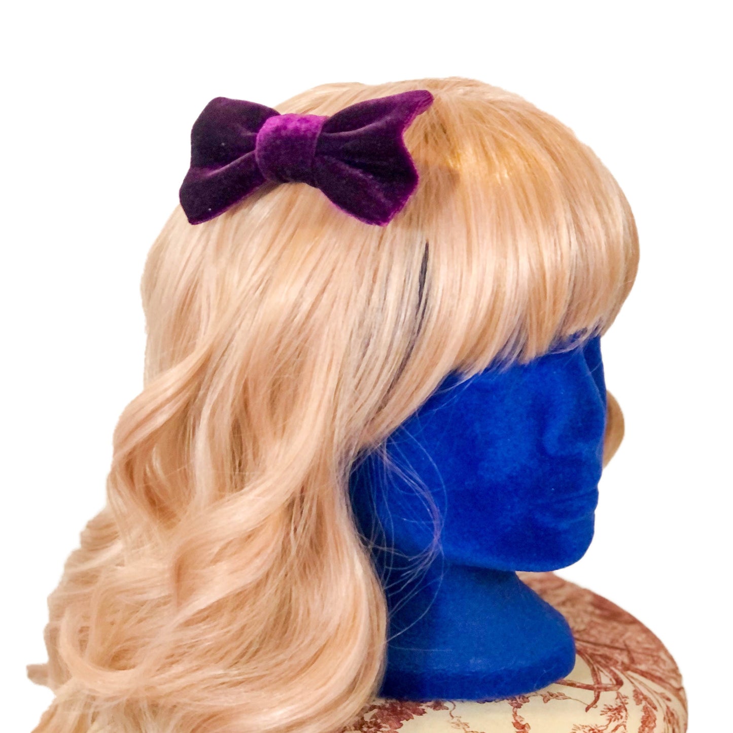 Photo of a hair bow made of fuzzy purple velour on a wig