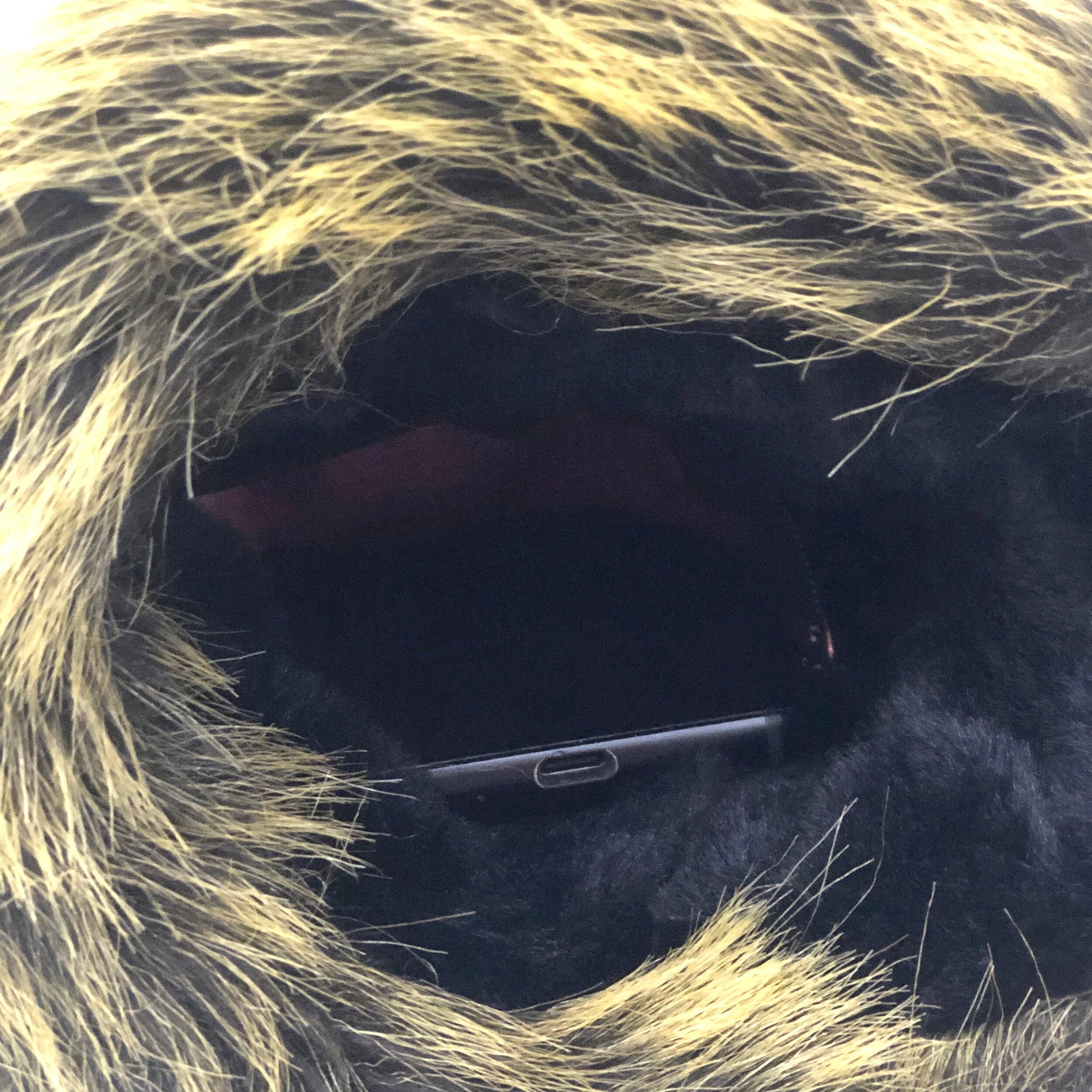 Close up view of a muff with strap made of brown faux fur showing interior pocket